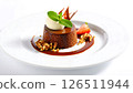 A decadent chocolate dessert on a white plate, garnished with cream, mint, nuts, and strawberry. 126511944