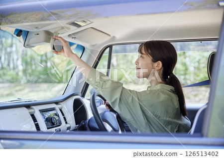 Japanese female driver adjusting the rearview mirror of her car 126513402