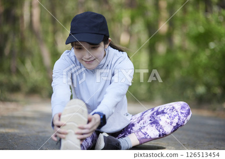 A woman stretching in a lush green forest. A woman stretching in a lush green forest. 126513454