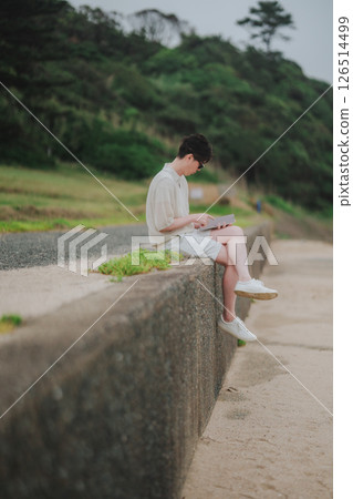 A man in his 20s working remotely at a resort 126514499