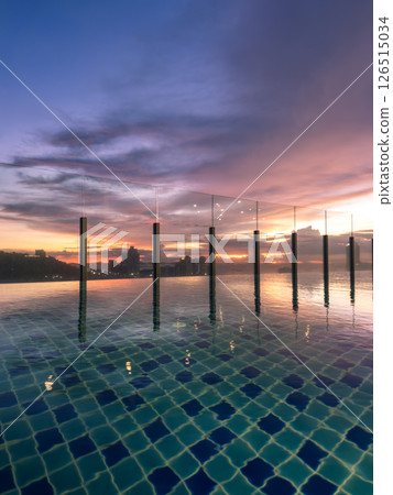 Stunning sunset view over a city skyline from a rooftop pool during twilight hours 126515034