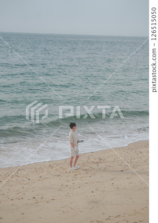 A man in his 30s wearing sunglasses working remotely at a resort 126515050