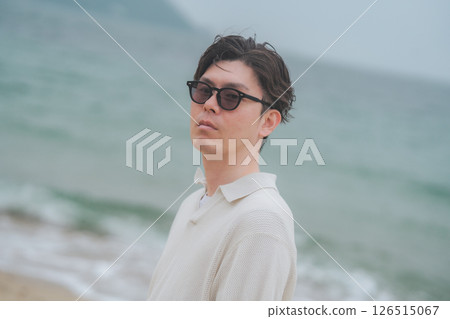 A man in his 30s wearing sunglasses working remotely at a resort 126515067