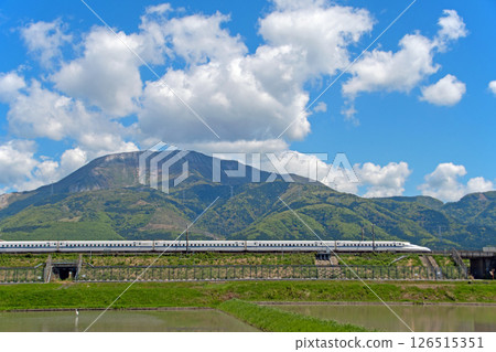 東海道新幹線N700S在晴朗的天空下穿過伊吹山的綠色植物。 東海道新幹線N700S在晴朗的天空下穿過伊吹山的綠色植物。 126515351