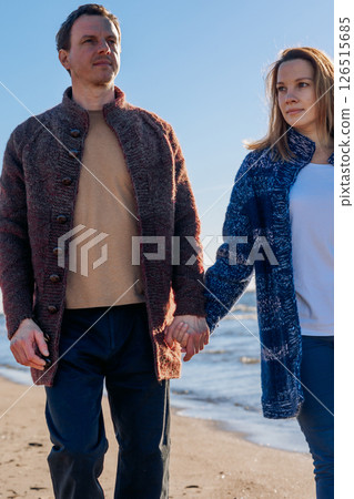 Portrait loving couple walks on beach along sea on sunny autumn day. Weekend and lifestyle concept. Vertical photo. High quality photo 126515685