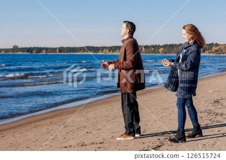 Loving couple walks on beach along sea on sunny autumn day. Weekend and lifestyle concept. High quality photo Loving couple walks on beach along sea on sunny autumn day. Weekend and lifestyle concept. High quality photo 126515724