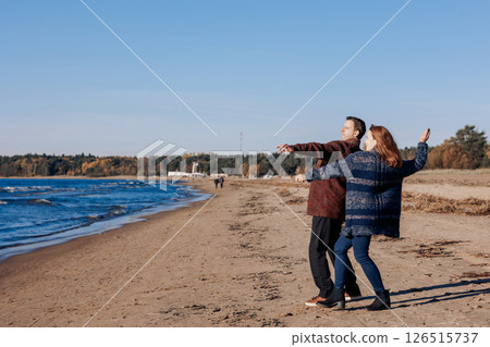 Young carefree couple in love throwing pebbles, shells, stones into sea outdoors. Fun family game together. High quality photo 126515737