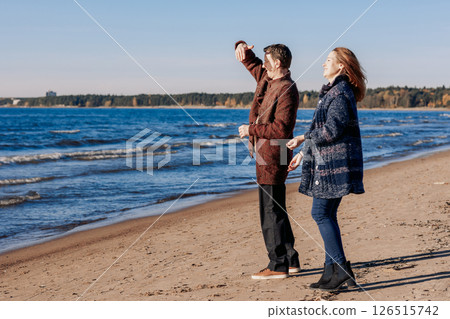 Loving couple walks on beach along sea on sunny autumn day. Weekend and lifestyle concept. High quality photo 126515742