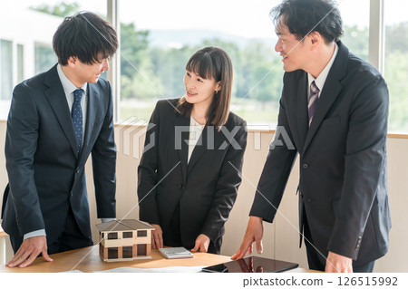 Male and female businessmen having a meeting in front of a house model and blueprints 126515992
