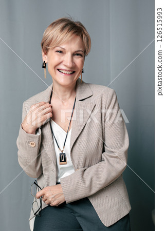 Portrait of happy woman. Confident, successful mature woman on light gray background. Looking at camera. High quality photo 126515993