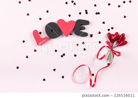 Valentine's day romantic party concept. Gift word LOVE and bouquet of sweet hearts decorations on pink background. Top view, flat lay, copy space 126516011