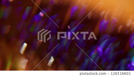 Crystal radiance. Blur sparkle. Multicolored particles lens flare turning on purple yellow blue orange bokeh light background. 126516601
