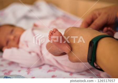 A tender moment featuring a newborn baby's tiny foot held by a caring hand, resting on a soft pink blanket, symbolizing new life and parental connection A tender moment featuring a newborn baby's tiny foot held by a caring hand, resting on a soft pink blanket, symbolizing new life and parental connection 126517057