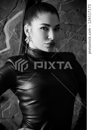 A striking black and white portrait of Hailey Bieber, a young woman with a high ponytail, wearing a black leather outfit and silver earrings, posing confidently A striking black and white portrait of Hailey Bieber, a young woman with a high ponytail, wearing a black leather outfit and silver earrings, posing confidently 126517173