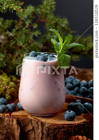 Blueberry smoothie in glass and fresh berries on a pine stump. Blueberry smoothie in glass and fresh berries on a pine stump. 126518526