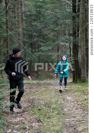 Exploring the serene forest trails on a cool day filled with laughter and discovery, as an adult guides a curious child through nature's beauty 126518615