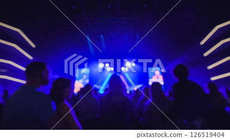 Crowd enjoying live music concert with blue stage lights illuminating audience 126519404