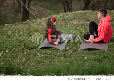 Outdoor yoga practice brings peace and connection between a child and an adult surrounded by nature on a spring afternoon, creating a serene atmosphere and joyful bond 126519748