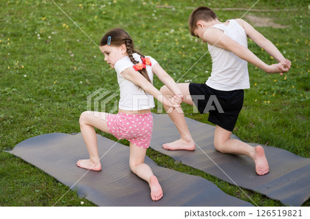 Children stretching together outdoors on yoga mats. Healthy active lifestyle for kids. 126519821