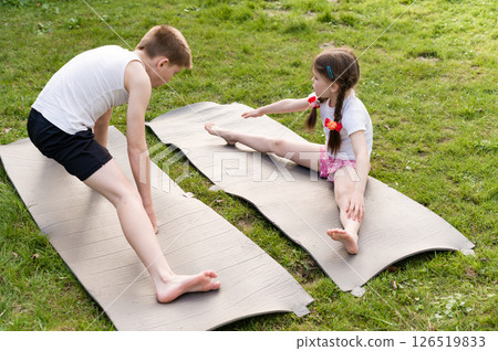 Brother and sister stretching outdoors on yoga mats. Enjoying a sunny day of fitness and flexibility. 126519833