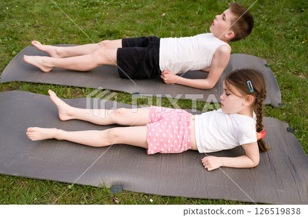 Children doing stretching exercises outdoors on mats. 126519838