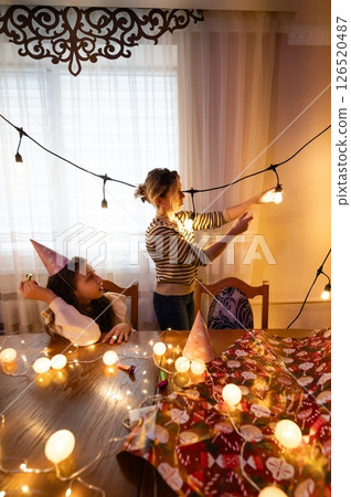 Creative celebration preparations with lights and decor taking place in a cozy indoor space during the evening hours as friends gather for a joyful event Creative celebration preparations with lights and decor taking place in a cozy indoor space during the evening hours as friends gather for a joyful event 126520487