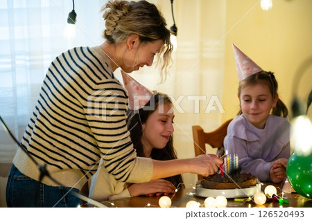 Joyful family celebration at home with birthday cake and cheerful children enjoying a special moment together while festive decorations illuminate the cozy atmosphere 126520493