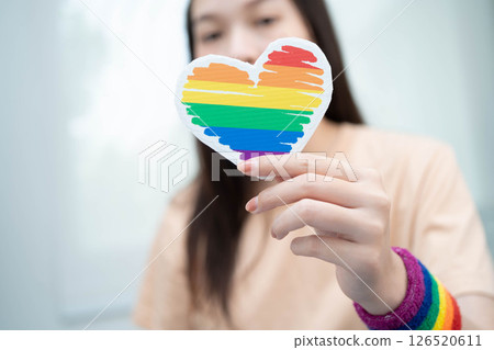 Asian woman holding LGBT heart with rainbow flag. Asian woman holding LGBT heart with rainbow flag. 126520611