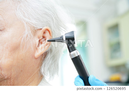 Otolaryngologist or ENT physician doctor examining senior patient ear with otoscope, hearing loss problem. Otolaryngologist or ENT physician doctor examining senior patient ear with otoscope, hearing loss problem. 126520695