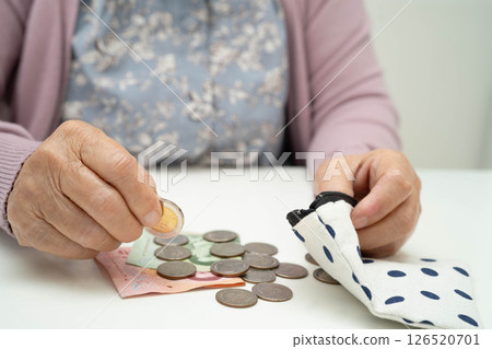 Asian senior or elderly old lady woman holding counting coin money in bag. Poverty, saving problem in retirement. Asian senior or elderly old lady woman holding counting coin money in bag. Poverty, saving problem in retirement. 126520701