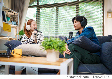 Two young people recording podcast at home with headphones and microphones 126521183