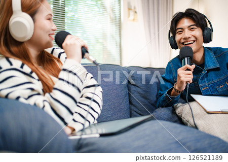 Young man speaking in podcast with headphones and microphone at home Young man speaking in podcast with headphones and microphone at home 126521189
