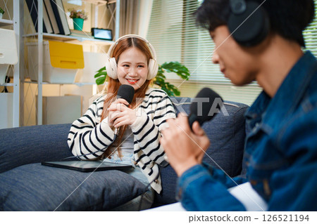 Podcast conversation between young man and woman with headphones and microphones Podcast conversation between young man and woman with headphones and microphones 126521194