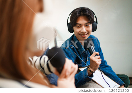 Young man speaking in podcast with headphones and microphone at home 126521200