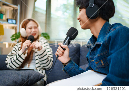 Young man speaking in podcast with headphones and microphone at home 126521201