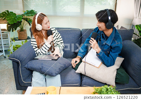 Two young people recording podcast at home with headphones and microphones 126521220
