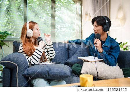 Two young people recording podcast at home with headphones and microphones Two young people recording podcast at home with headphones and microphones 126521225