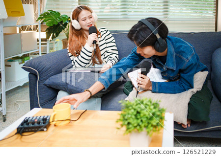 Two young people recording podcast at home with headphones and microphones Two young people recording podcast at home with headphones and microphones 126521229
