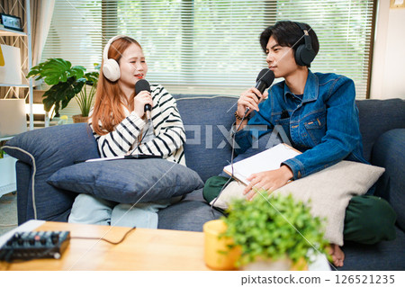 Two young people recording podcast at home with headphones and microphones Two young people recording podcast at home with headphones and microphones 126521235