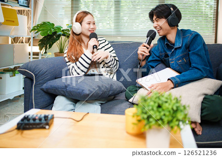 Two young people recording podcast at home with headphones and microphones 126521236