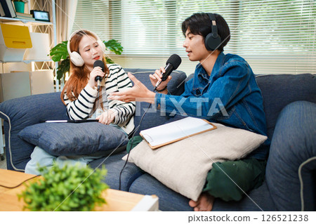 Podcast conversation between young man and woman with headphones and microphones 126521238