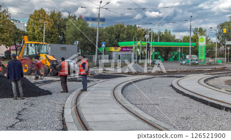 Asphalt roller and excavator on the road repair site during asphalting timelapse. Road construction equipment. 126521900