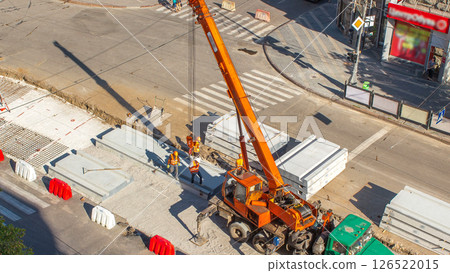 Installing concrete plates by crane at road construction site timelapse. Installing concrete plates by crane at road construction site timelapse. 126522015
