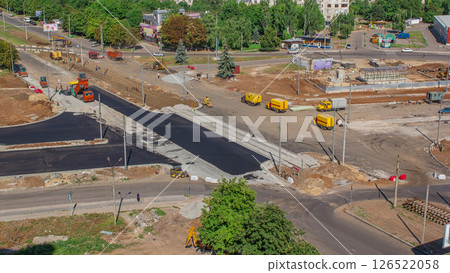 Asphalt paver, roller and truck on the road repair site during asphalting timelapse. Road construction equipment. 126522058