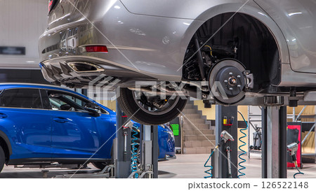 Car mechanic screwing and unscrewing car wheel of lifted automobile at repair service station timelapse 126522148