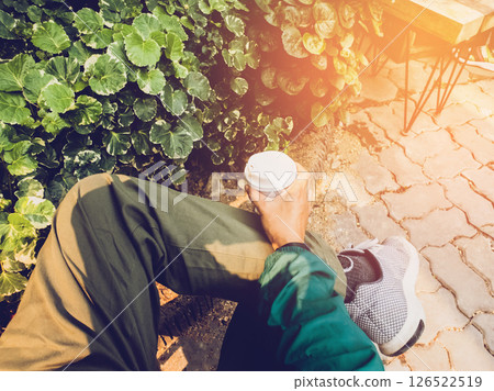 close up people sitting on the chair, Hand holding hot of coffee cup lifestyle of eating and drinking coffee outside with nature background and sunlight close up people sitting on the chair, Hand holding hot of coffee cup lifestyle of eating and drinking coffee outside with nature background and sunlight 126522519