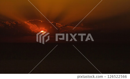 Sunset timelapse view: yellow bright sun disc on natural orange sky background with sun beams and rays of light Sunset timelapse view: yellow bright sun disc on natural orange sky background with sun beams and rays of light 126522566