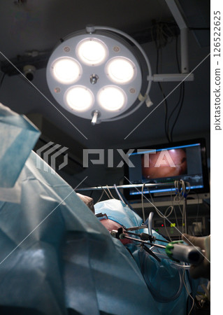 Veterinarians perform laparoscopic surgery on an animal patient under bright surgical lights, using special instruments and watching the procedure on a screen. Complex laparoscopic surgery on a pet. Veterinarians perform laparoscopic surgery on an animal patient under bright surgical lights, using special instruments and watching the procedure on a screen. Complex laparoscopic surgery on a pet. 126522625