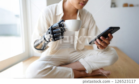 Young man with bionic arm drinking coffee and using smartphone 126523117