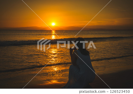 A woman looking at the sea at sunset A woman looking at the sea at sunset 126523450